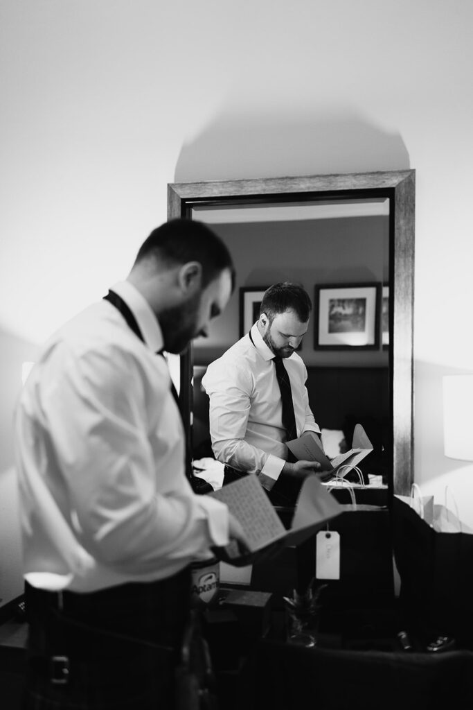 Groom opens wedding day card from Bride at Stables room at Meldrum House