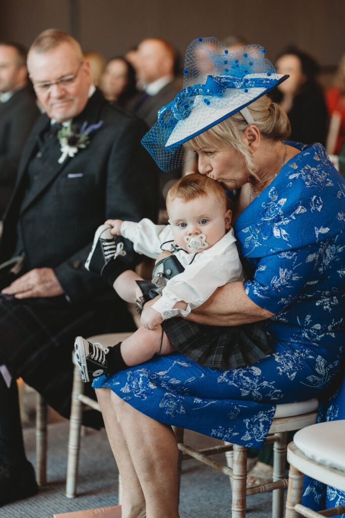 grandmother gently kisses grandson during parents wedding at meldrum house