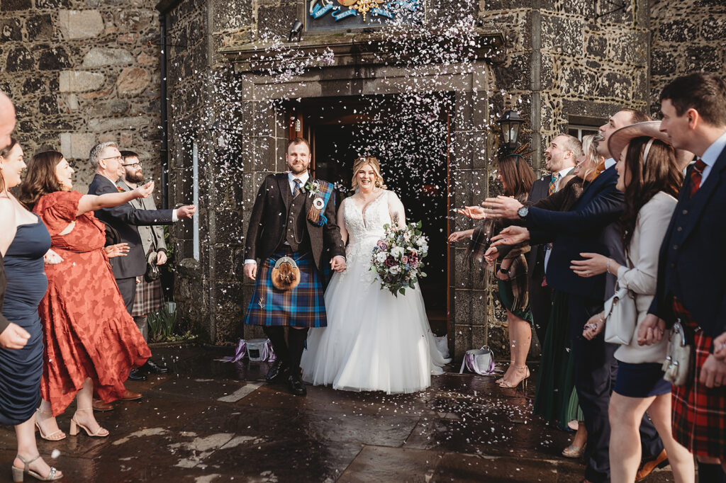 Aberdeenshire bride and groom showered with confetti outside main door of Meldrum House