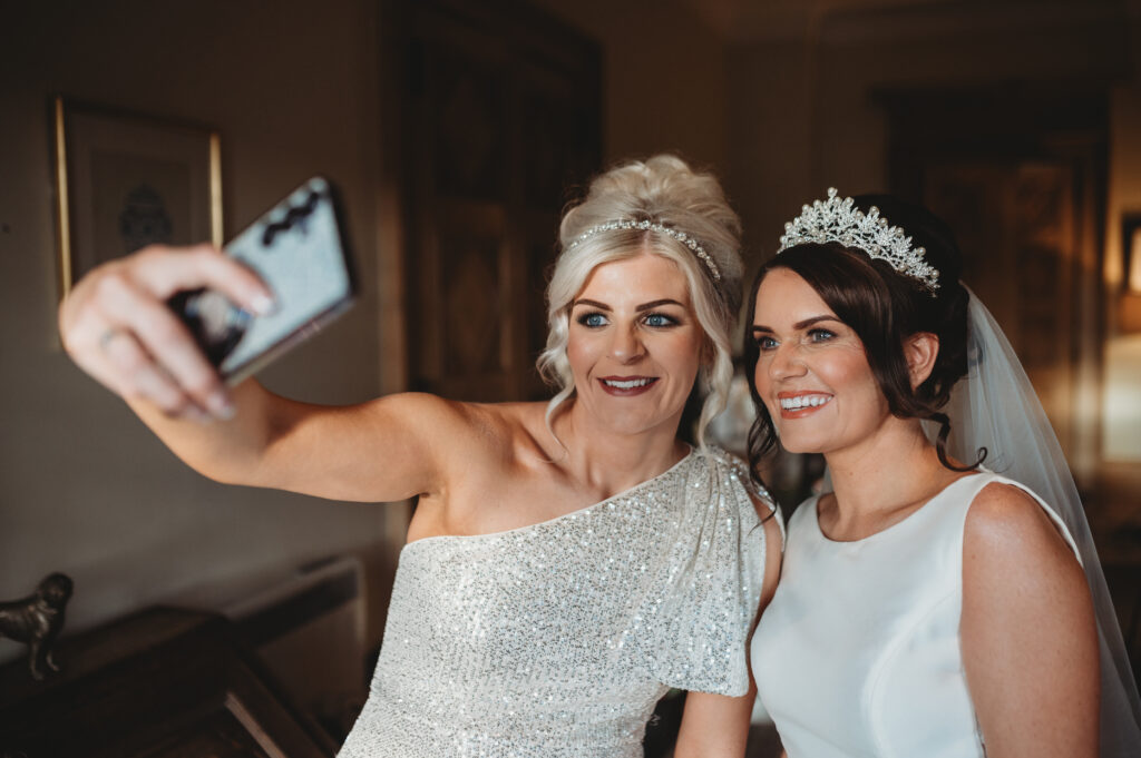 Aberdeenshire bride and bridesmaid take pictures at meldrum house aberdeenshire