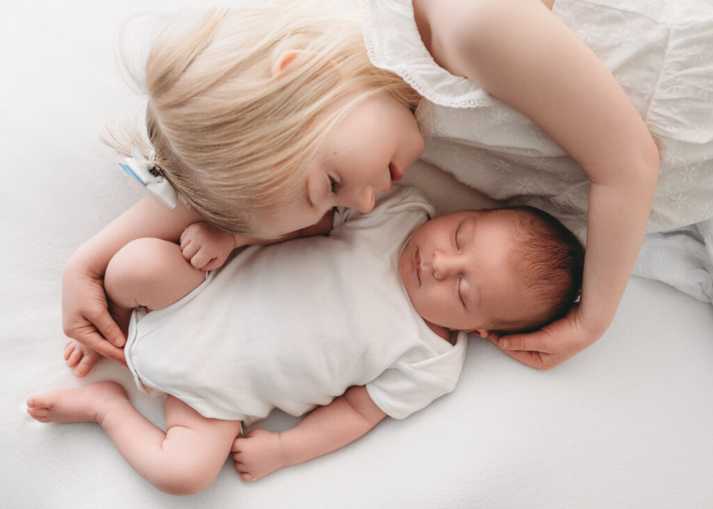 Sister holds newborn sibling during newborn session in Aberdeenshire